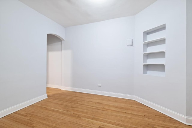 empty room featuring light hardwood / wood-style flooring and built in shelves