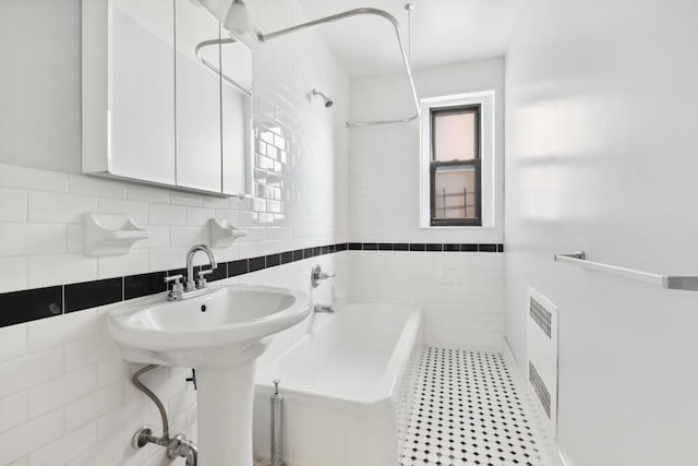 bathroom featuring tile walls, sink, a tub, and tile patterned floors