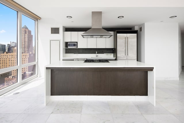 247 W 46th St Unit 1803, New York City, NY 10036 - kitchen featuring island exhaust hood, stainless steel microwave, white cabinetry, and light countertops