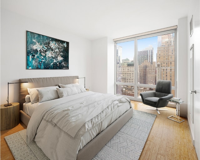 bedroom with a view of city and light wood-type flooring