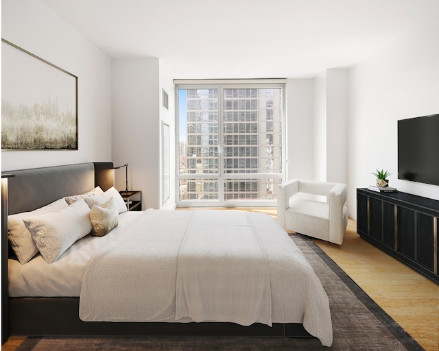 bedroom featuring a wall of windows and wood finished floors