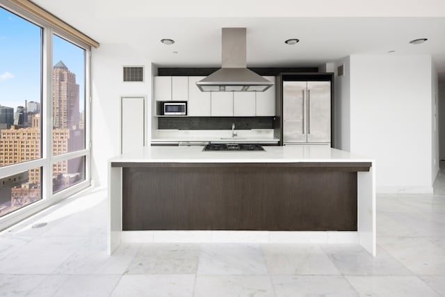 kitchen with island range hood, stainless steel appliances, visible vents, light countertops, and modern cabinets