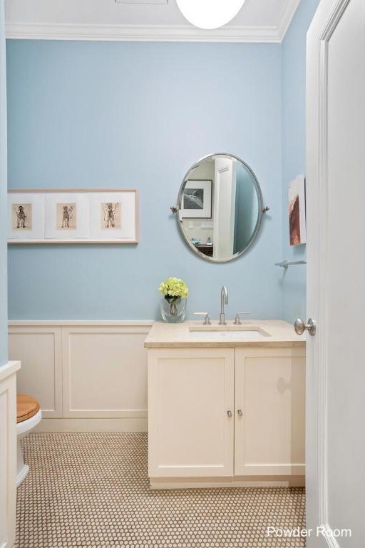 bathroom with toilet, vanity, and crown molding