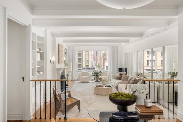 sitting room with ornamental molding and beamed ceiling