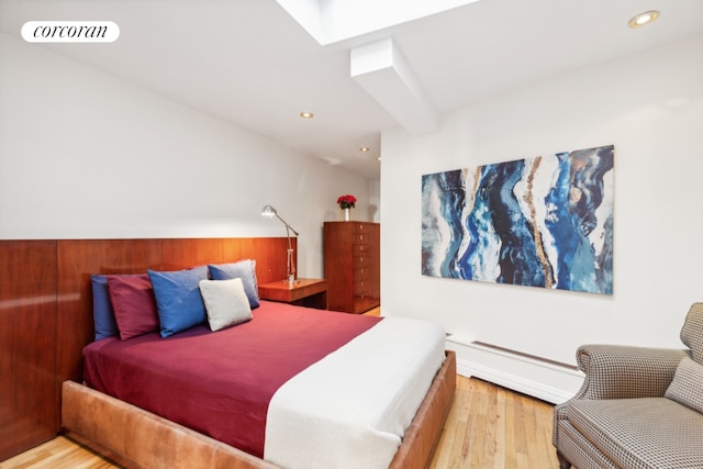 bedroom featuring a baseboard heating unit and light wood-type flooring