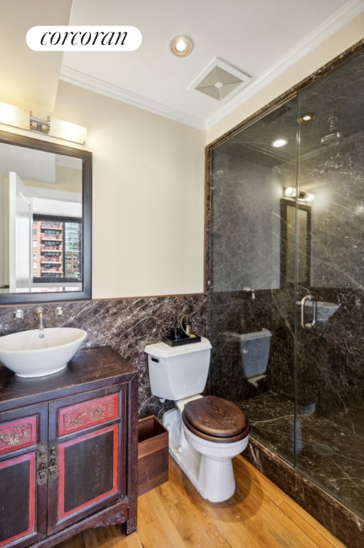 bathroom with wood-type flooring, vanity, tile walls, toilet, and crown molding