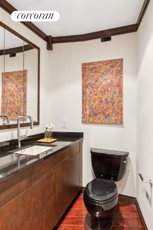 bathroom featuring toilet, crown molding, wood-type flooring, and vanity