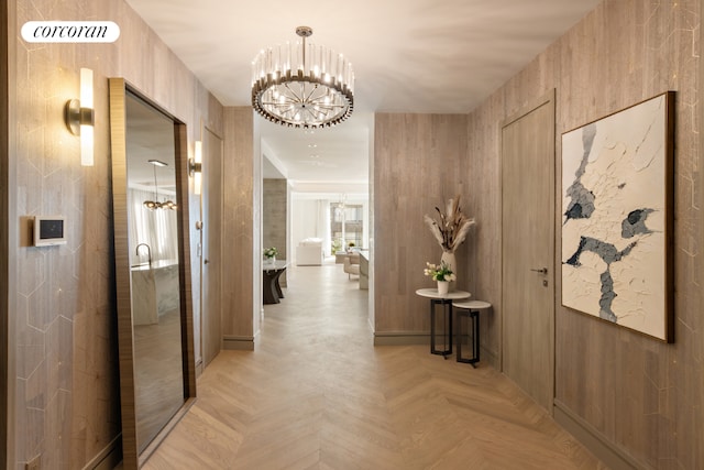 hallway with light parquet flooring and an inviting chandelier