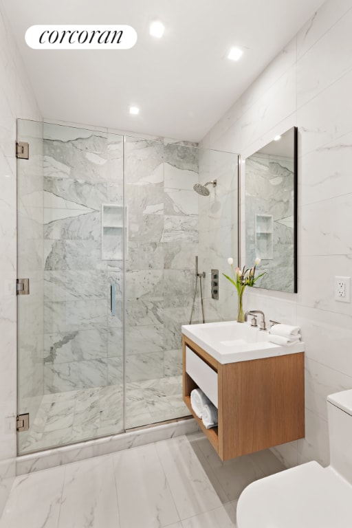 bathroom featuring a shower with shower door, vanity, and toilet