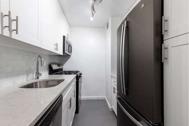 kitchen featuring a sink, white cabinetry, appliances with stainless steel finishes, backsplash, and light stone countertops