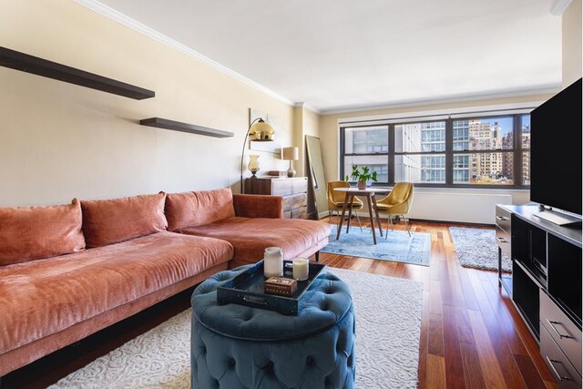 living area with ornamental molding, wood-type flooring, and baseboards