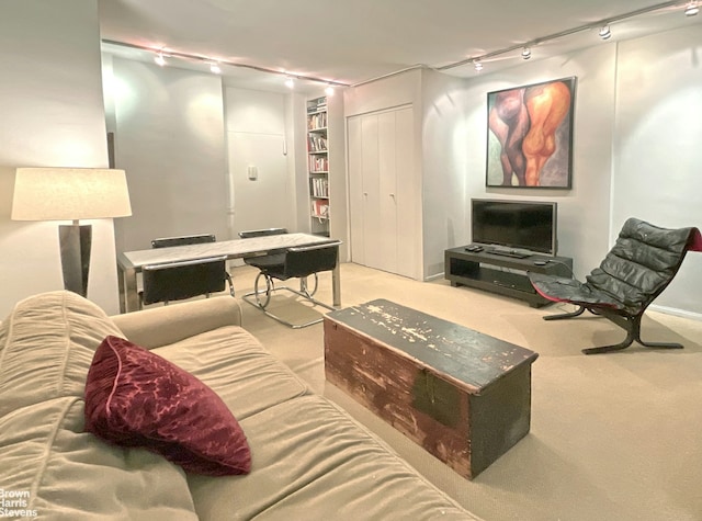 carpeted living area featuring rail lighting and built in shelves