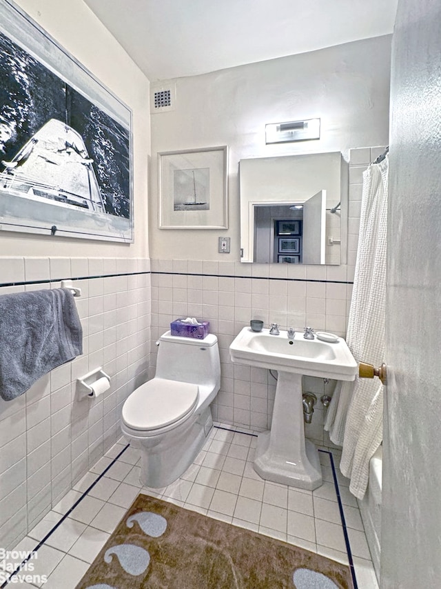 full bathroom with tile patterned floors, toilet, tile walls, and visible vents