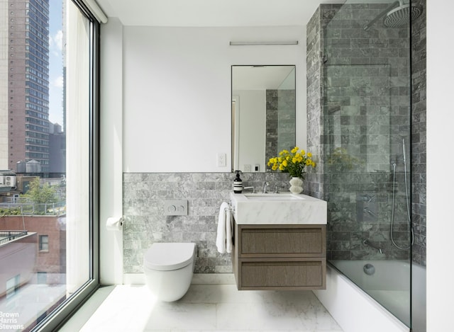 full bath with toilet, vanity, tile walls, marble finish floor, and a view of city