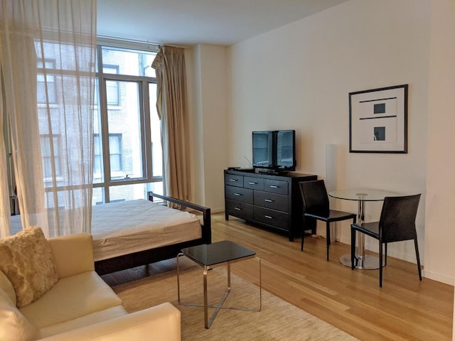 bedroom with a wall of windows and light hardwood / wood-style floors