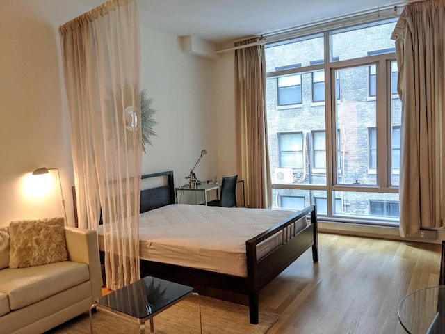 bedroom featuring a wall of windows and light wood-type flooring