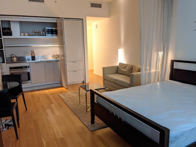 bedroom featuring bar and light wood-type flooring