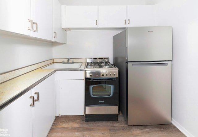 kitchen featuring dark wood-type flooring, stainless steel appliances, white cabinets, and sink