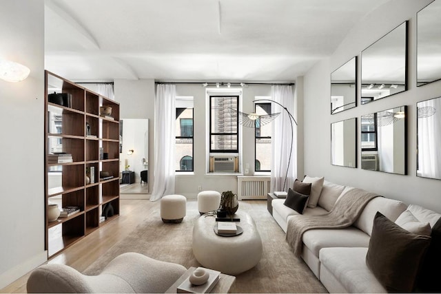 living room featuring radiator, a wealth of natural light, cooling unit, and light wood-type flooring