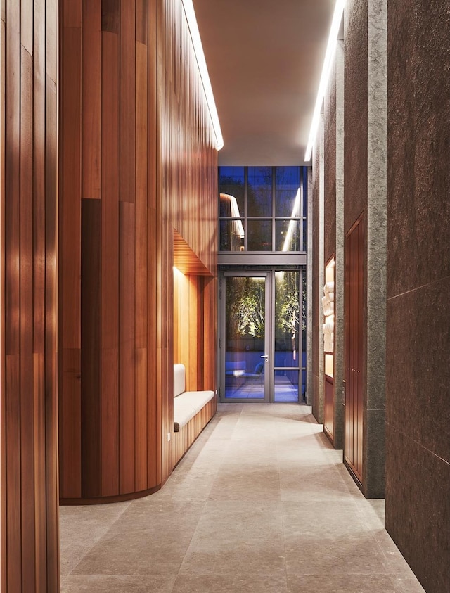 corridor featuring a high ceiling and wooden walls