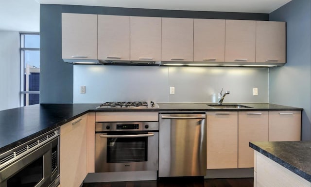 kitchen with appliances with stainless steel finishes, dark countertops, a sink, and range hood