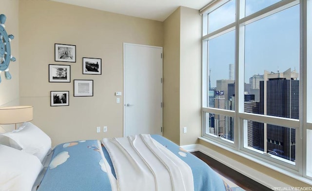 bedroom with a view of city, baseboards, and wood finished floors