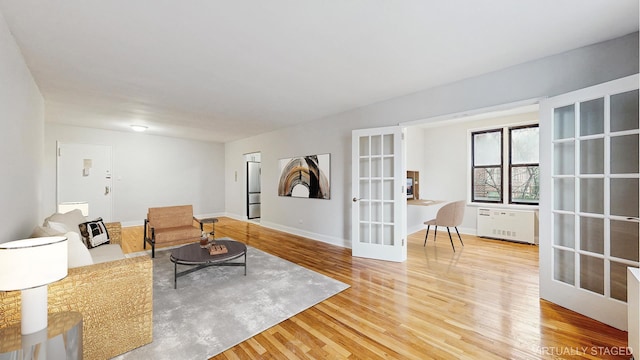 living room with french doors, baseboards, and wood finished floors