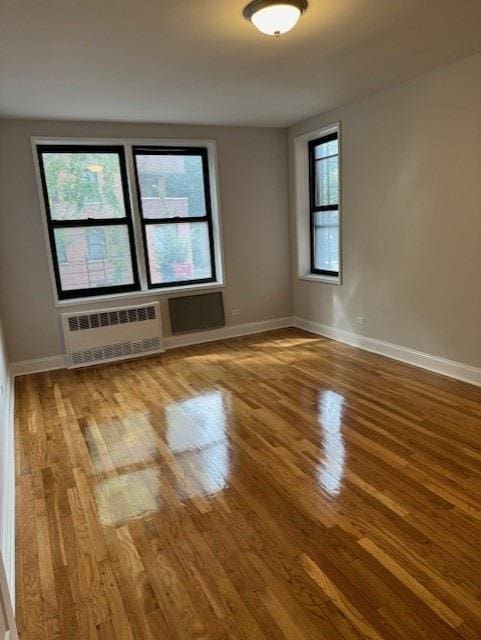 spare room with baseboards, wood finished floors, and radiator heating unit