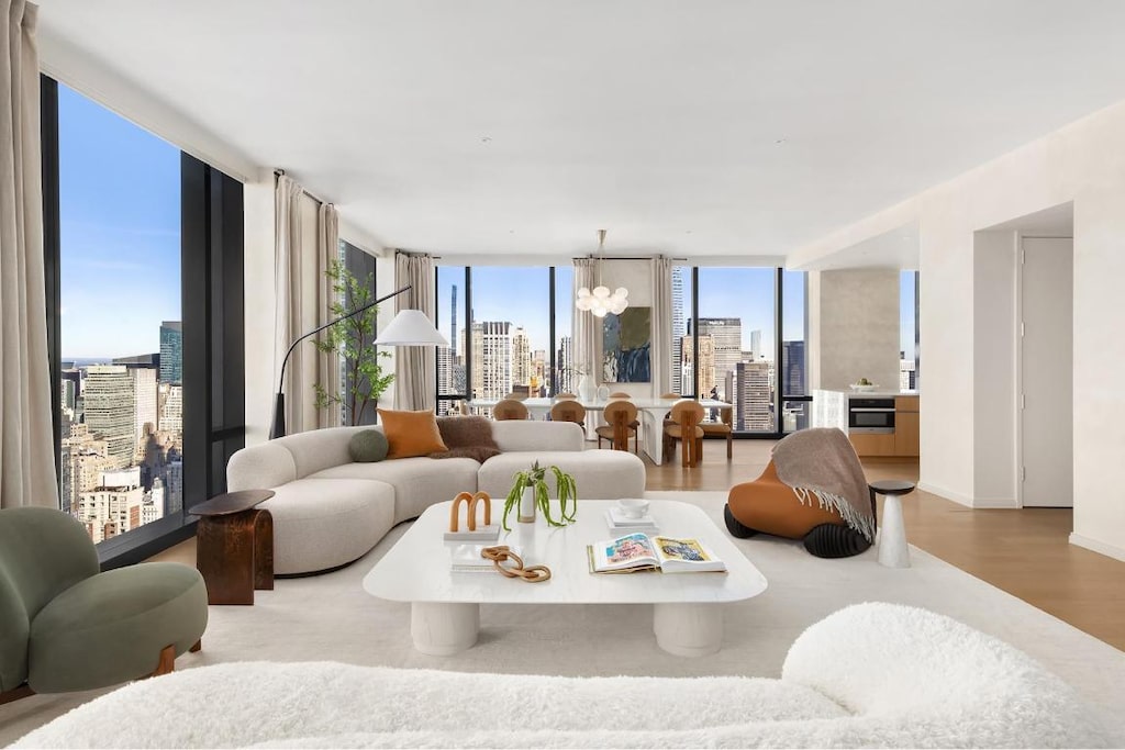 living room featuring expansive windows, a notable chandelier, and light wood-type flooring