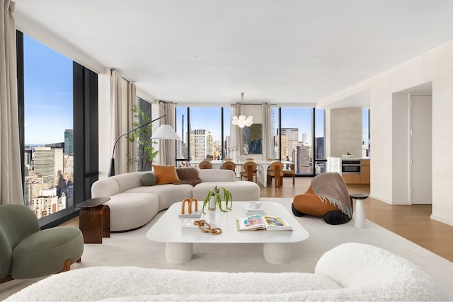 living area with a city view, wood finished floors, floor to ceiling windows, baseboards, and a chandelier