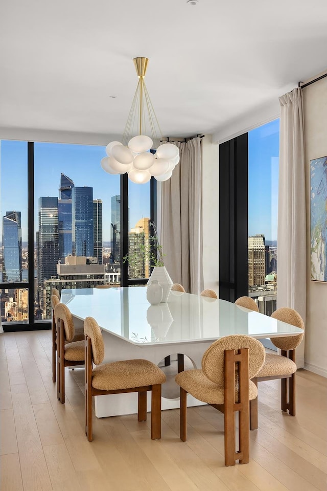 dining area with a city view, a wall of windows, light wood-style floors, and an inviting chandelier