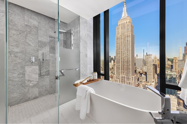 full bath featuring a soaking tub, a shower stall, a view of city, and tile walls