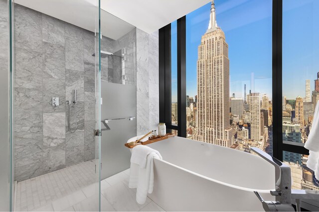 277 5th Ave Unit Ph53, New York City, NY 10016 - bathroom with a stall shower, a view of skyline, a freestanding bath, and a wall of windows