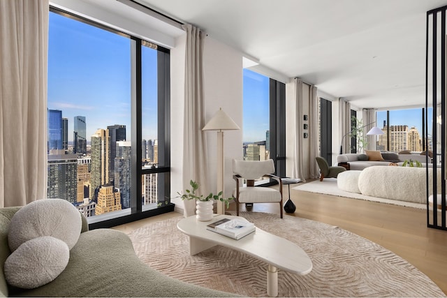 bedroom with a view of city, a wall of windows, and wood finished floors