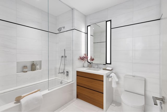 bathroom featuring toilet, tile walls, tile patterned flooring, bath / shower combo with glass door, and vanity