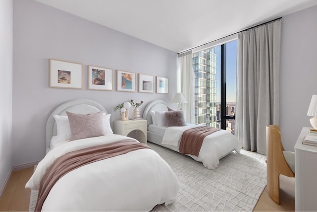 bedroom featuring a wall of windows, baseboards, and light wood finished floors