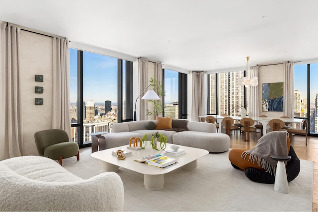 living area with a notable chandelier, floor to ceiling windows, a view of city, and wood finished floors