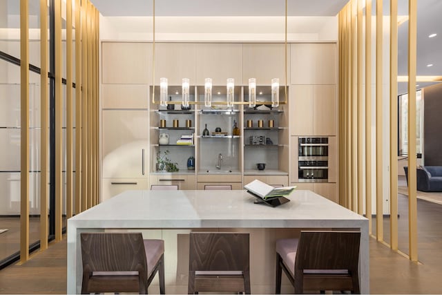 bar with a sink, stainless steel double oven, and dark wood-type flooring