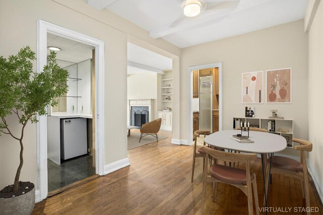 dining room with hardwood / wood-style flooring, ceiling fan, built in shelves, and beamed ceiling