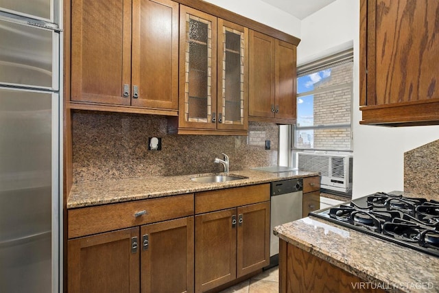 kitchen with light stone counters, sink, backsplash, and stainless steel appliances