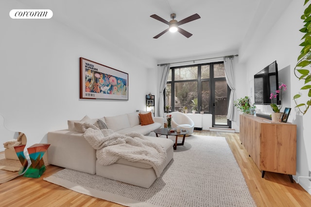 living room with light wood-style flooring, visible vents, and a ceiling fan