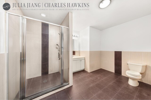 315 W 36th St Unit 12B, New York City, NY 10018 - full bathroom featuring vanity, toilet, a shower stall, wainscoting, and tile walls