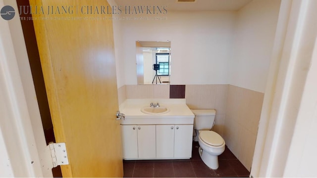 bathroom with toilet, vanity, tile patterned flooring, and tile walls