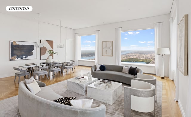 living room with an inviting chandelier, a wealth of natural light, light parquet flooring, and a water view