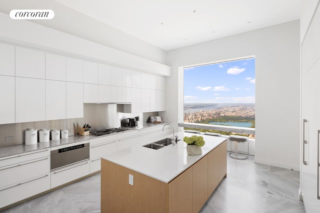 kitchen featuring white cabinetry, a water view, sink, and a center island with sink