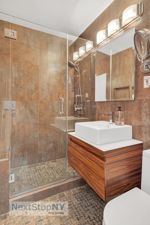 bathroom with vanity, tile walls, an enclosed shower, and toilet