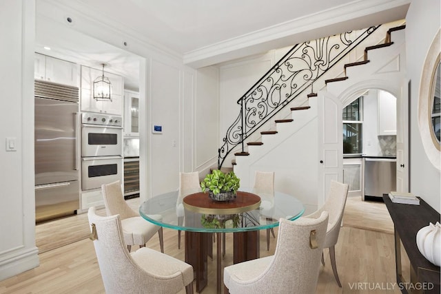 dining area with crown molding, a chandelier, and light hardwood / wood-style flooring