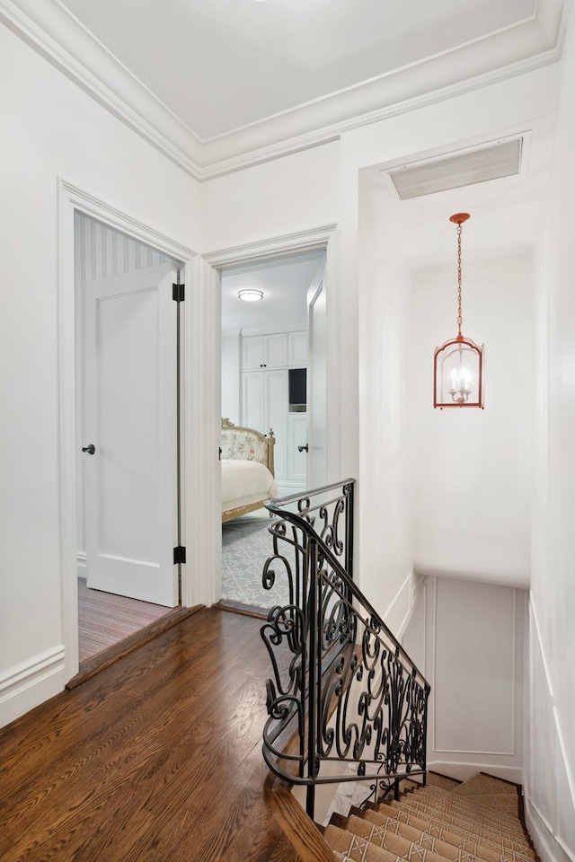 hall featuring ornamental molding, a notable chandelier, an upstairs landing, and wood finished floors