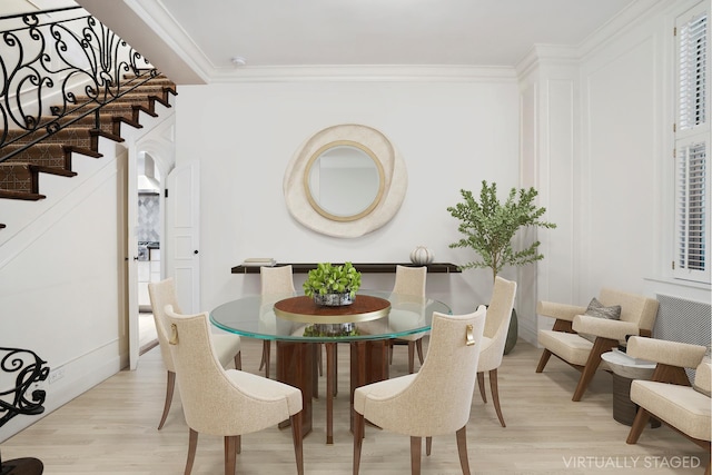 dining room with light wood finished floors, stairway, and crown molding