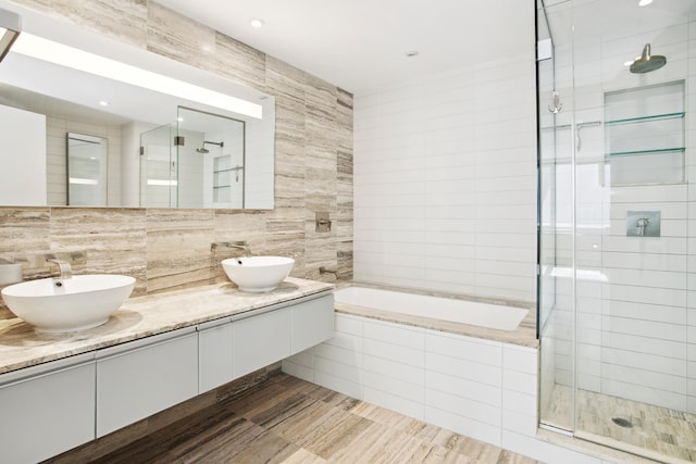 322 W 57th St Unit 55S1, New York City, NY 10019 - bathroom with tile walls, a stall shower, a relaxing tiled tub, backsplash, and double vanity